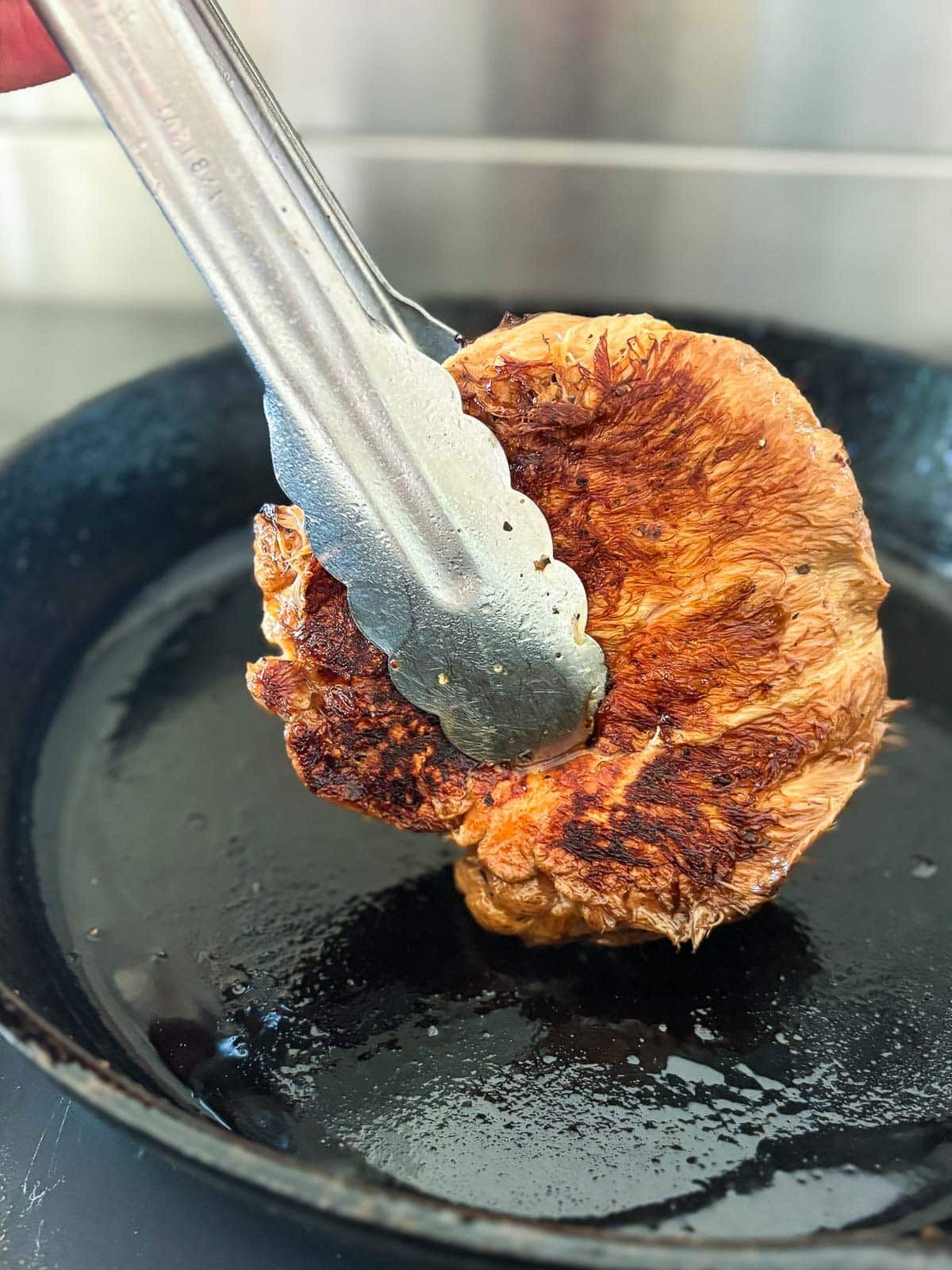 Browning both sides of the whole mushroom, now compressed to 1 ½ inches thick.